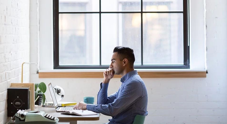 Man thinking at his desk looking at his computer screen 