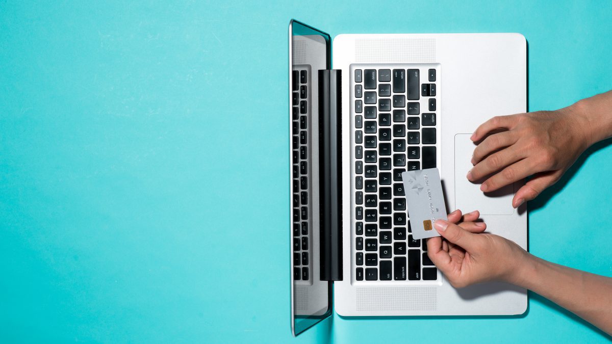 person holding a credit card above the keyboard of their laptop