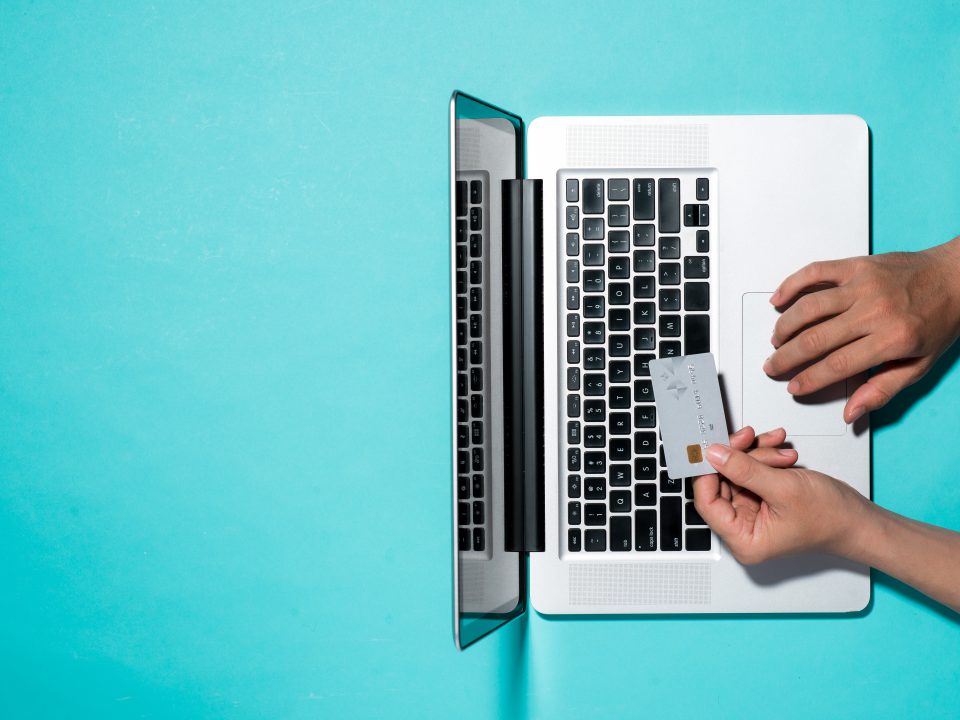 person holding a credit card above the keyboard of their laptop