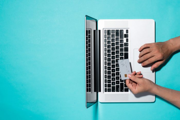 person holding a credit card above the keyboard of their laptop